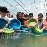 Menteri Susi Pudjiastuti saat menebar benih lele di komplek SMA Trensains Tebuireng Jombang, Minggu (13/8/2017). foto: ROMZA/ BANGSAONLINE