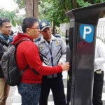 Pengguna parkir didampingi Staf Dishub dan juru parkir mencoba menggunakan parkir meter yang dipasang di depan kantor humas di Jl Jimerto.