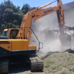 Eskavator saat merobohkan rumah di Desa Dadapan, Kabat, Banyuwangi yang lahannya sempat menjadi sengketa.