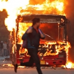 Seorang pria berlari melewati sebuah bus yang terbakar yang dibakar oleh para demonstran selama protes terhadap undang-undang kewarganegaraan baru, di Delhi, India. foto: theguardian