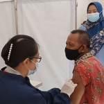 Kepala Puskesmas Pagu drg. Dewi Kasanah Murtiningsih (berdiri) saat menyaksikan pemberian Vaksin AstraZaneca kepada salah satu lansia laki-laki di Puskesmas Pagu. (foto: MUJI HARJITA/ BANGSAONLINE)