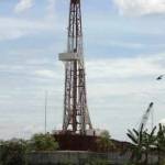 Rig PAD B JOB P-PEJ tampak menjulang tinggi di sekitar pertanian dan perkampungan warga. 