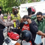 Petugas dari Satlantas Polresta Sidoarjo saat membagikan masker untuk pengendara di Jalan Raya Taman Pinang.