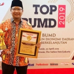 Irsyad Yusuf memamerkan piagam dan trofi penghargaan.