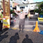 Petugas menyemprotkan disinfektan kepada anggota yang baru masuk mapolres Jember.