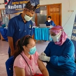 Lutfi Mahmudiono, Ketua DPD Partai Nasdem Kabupaten Kediri saat memberi semangat kepada salah satu warga yang terlihat ketakutan ketika hendak disuntik vaksin. foto: MUJI HARJITA/ BANGSAONLINE