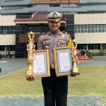 Kasatlantas Polres Tuban AKP Ricky Tri Dharma menunjukkan piala dan piagam penghargaan untuk Posyan Terbaik.