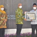 Kepala BKN RI, Bima Haria Wibisana didampingi Gubernur Jawa Timur, Khofifah Indar Parawansa menyerahkan penghargaan kepada Bupati Gresik Fandi Akhmad Yani. foto: SYUHUD/ BANGSAONLINE