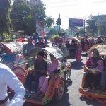 Pengantin nikah massal diarak menggunakan becak hias dalam puncak perayaan resepsi. foto: MURSIDI/ BANGSAONLINE