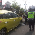 Petugas kepolisian saat mengevakuasi mobil yang tersangkut di median Jalan Pahlawan, Sidoarjo.