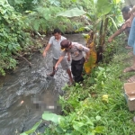 Petugas dibantu warga saat hendak mengevakuasi jasad bayi.