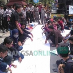 Massa saat membubuhkan tanda tangan di banner raksasa menuntut perbaikan jalan.