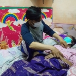 Agus Setyo Budi menemani istrinya yang tengah terbaring di tempat tidur karena sakit.