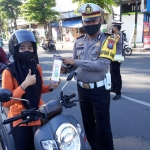 Kasatlantas Polres Pamekasan AKP Mokhammad Munir saat memberikan reward kepada pengendara sepeda motor yang tertib berlalu lintas di Area Monumen Arek Lancor Pamekasan.