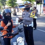 Kasatlantas Polres Pamekasan AKP Mokhammad Munir saat memberikan reward kepada pengendara sepeda motor yang tertib berlalu lintas di Area Monumen Arek Lancor Pamekasan.