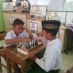 Dua bocah SD peserta kejuaraan catur di Bangilan saat sedang bertanding. foto: AHMAD/ BANGSAONLINE