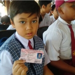 Seorang siswa sedang memegang Kartu Identitas Anak.