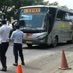 Petugas Dinas Perhubungan mengarahkan bus patas untuk masuk ke dalam terminal. Foto: zainal abidin/ BANGSAONLINE