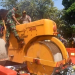 Kapolres Kediri Kota AKBP Anthon Heryadi bersama Pjs Wali Kota Jumadi saat menaiki alat berat melakukan pemusnahan miras berbagai merk. foto: ARIF K/ BANGSAONLINE