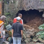 Personel BPBD Kota Batu saat menangani plengsengan rumah yang tergerus akibat curah hujan tinggi.