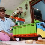 Basunie saat membuat miniatur Bus dan truk di bengkel kayun depan rumahnya. Foto: RONY S/BANGSAONLINE