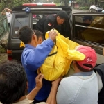 Jenazah saat dievakuasi petugas dibantu warga setempat.
