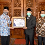 Bupati Pungkasiadi saat menerima penghargaan bidang KB yang diserahkan oleh Kepala Perwakilan BKKBN Provinsi Jawa Timur, Sukaryo Teguh Santosa. (foto: ist).