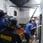 Petugas melakukan pembasahan terhadap sisa-sisa api.