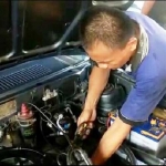 Jono, pemilik bengkel tradisional saat melakukan servis sebuah mobil.