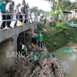 Muspika Soko bersama warga bahu membahu menyingkirkan sampah yang nyangkut di bawah jembatan. foto: AHMAD/ BANGSAONLINE