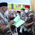 Bupati Gresik, Fandi Akhmad Yani, saat menyerahkan sertifikat tanah. Foto: SYUHUD/ BANGSAONLINE