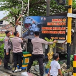 Petugas Polsek Candi saat melakukan pemasangan spanduk imbauan di perlintasan KA tak berpalang.