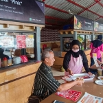 Pengelola Kedai Pink, Putri Della Wulandari, saat menyajikan pesanan kepada pembeli. Foto: SYUHUD/BANGSAONLINE