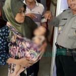 Seorang ibu menggendong ananknya sambil menunjukkan luka akibat digigit kera liar.