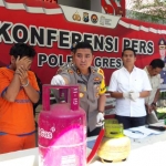 Kapolres Gresik AKBP Wahyu S Bintoro menunjukkan tersangka berikut tabung elpiji 12 Kg dan 3 Kg yang disita. foto: SYUHUD/ BANGSAONLINE