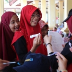 Anggota Gerakan Cinta Bahasa Indonesia (GCBI) saat sedang memberikan kuis kepada warga di Alun-alun Sidoarjo.
