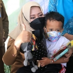 Bupati Mojokerto, Ikfina Fahmawati, saat memangku seorang anak yang mengikuti imunisasi.