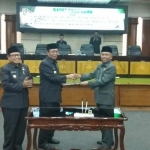 Fathul Huda dan Miyadi berjabat tangan usai menandatangai draft persetujuan tiga raperda.