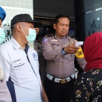 Kanit Regident Ipda Syaiful Ilmi saat mengecek suhu tubuh pengunjung yang hendak mengurus SIM di Satpas Satlantas Polres Bangkalan menggunakan alat thermal gun.