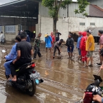 Petugas BPBD Kota Batu dibantu warga saat membersihkan lumpur yang sempat menutup jalan raya.