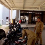 Petugas Dispol PP saat menggembosi ban sepeda motor yang parkir di areal terlarang kantor pemkab.