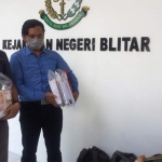 Petugas membawa barang bukti segepok uang pecahan Rp 100 ribu yang dimasukkan ke dalam plastik.