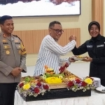 Ketua PWI Kediri Bambang Iswahjoedhi saat menyerahkan potongan tumpeng kepada Kasi Humas AKP Sriati disaksikan oleh Kapolres Kediri AKBP Bimo Ariyanto. Foto: MUJI HARJITA/ BANGSAONLINE.com