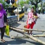 BLOKADE – Warga memasang kayu bambu memblokade Jalan Sukomoro-Pace saat memprotes perbaikan rel KA, Rabu (16/9). foto: soewandito/BANGSAONLINE