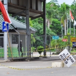 Pintu masuk utama dipasang plastik berwarna kuning hitam oleh pemilik lahan bernama Djakimin. 