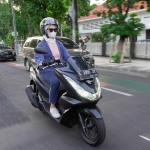 Ilustrasi seorang perempuan bermotor dengan riding gear yang aman dan benar.