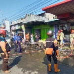 Petugas pemadam kebakaran saat berusaha memadamkan api yang membakar sebuah toko di Jombang.