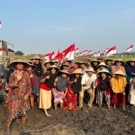 Sudiono Fauzan (baju putih) bersama petani Desa Masangan di tengah sawah berlumpur usai mengikuti upacara.