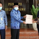 SIMBOLIS: Pj. Bupati Hudiyono menyerahkan bansos ke penyintas Covid-19, di Pendopo Delta Wibawa, Kamis (17/12/2020).