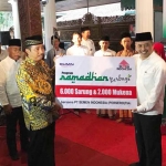 Direktur SDM dan Hukum Agung Yunanto (baju putih) secara simbolis menyerahkan bantuan sarung dan mukena kepada bupati Rembang Abdul Hafidz. foto: SYUHUD/ BANGSAONLINE